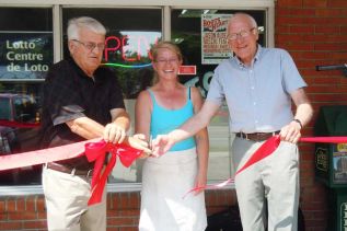  South Frontenac Mayor Gary Davison and South Frontenac Councilor John McDougall assist Coleen Whan in cutting the ribbon at the Harrowsmith Bakery and Variety